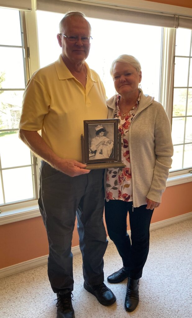 Chris and Debbie Karlberg 2024, holding 1954 photo of Kay Antonietti and Baby Charley